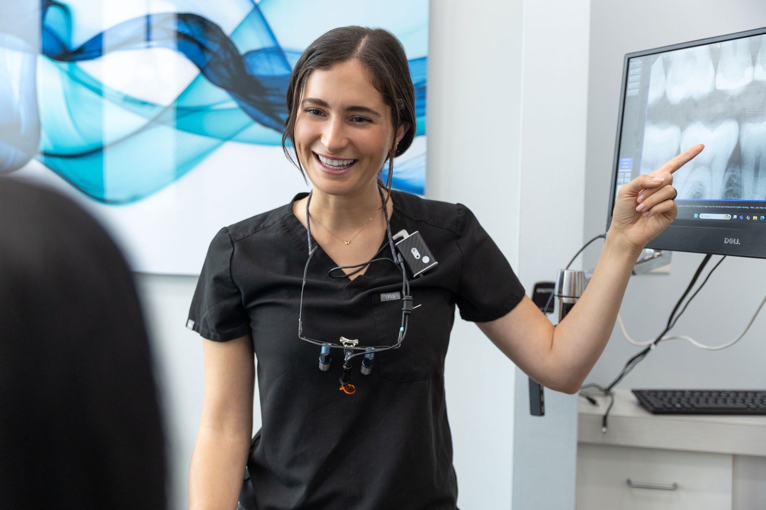 Village Dental dentist pointing at dental X-rays in Village, CO clinic