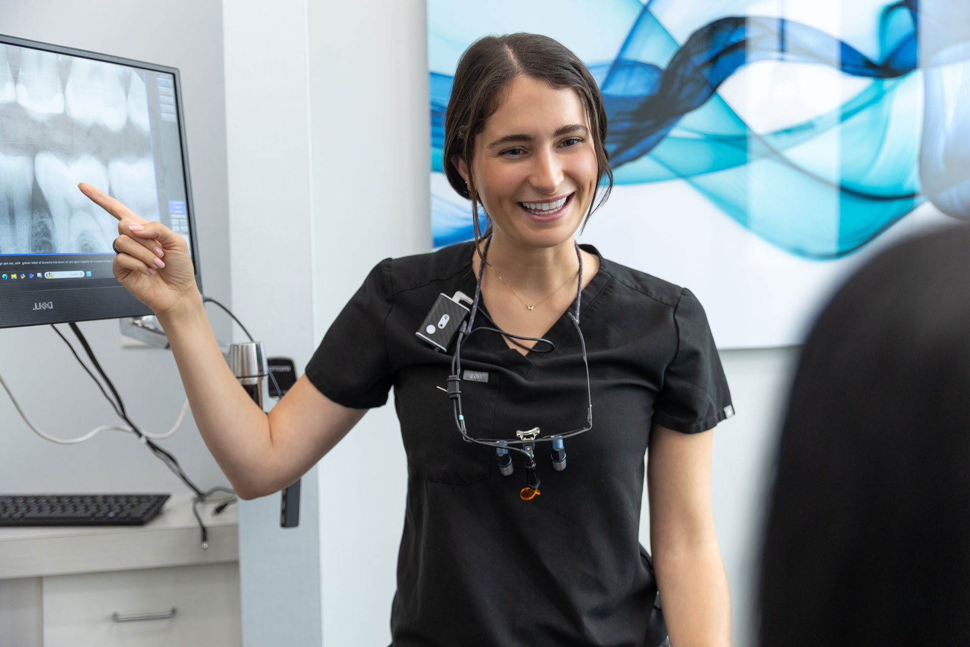 Village Dental dentist pointing at X-rays exam in Village, CO clinic
