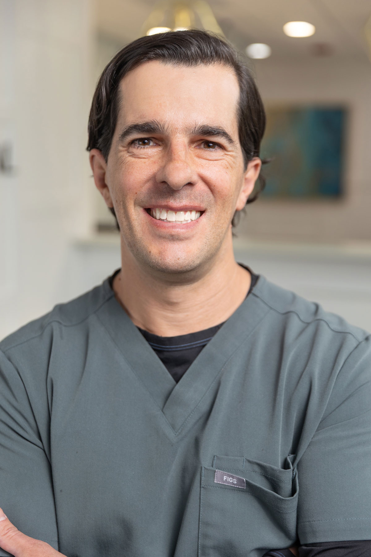 Smiling male dentist in scrubs at Village Dental in Village, CO