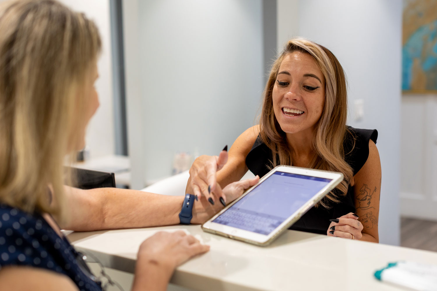 Village Dental staff assisting patient with tablet in Village, CO reception area