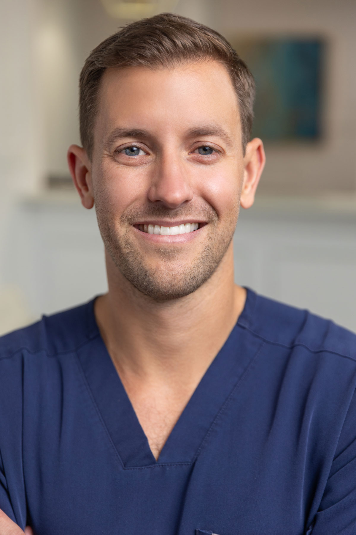 Smiling dentist wearing blue scrubs at Village Dental in Village, CO